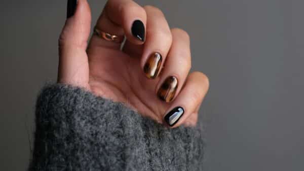 person wearing silver ring with black manicure