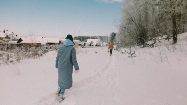 man in gray jacket walking on snow covered ground during daytime