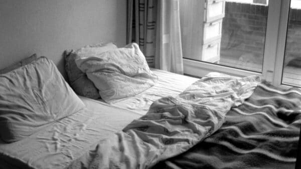 A bed is unmade near a window.