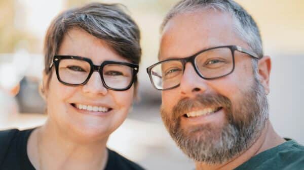 A smiling couple wearing glasses outdoors