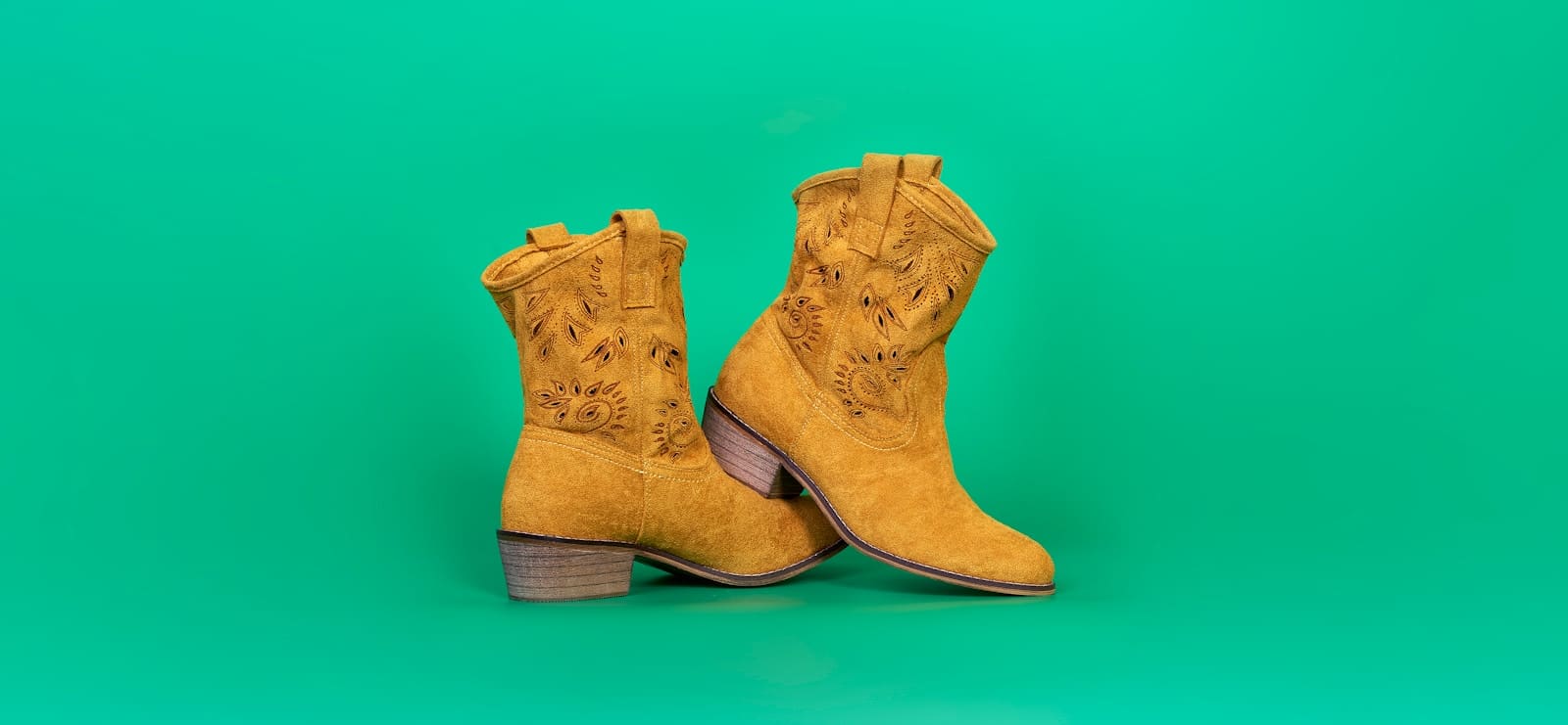 a pair of yellow cowboy boots on a green background