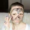 a woman with a face mask on holding her hand up to her face