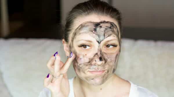 a woman with a face mask on holding her hand up to her face