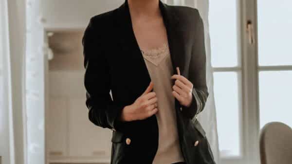 woman in black blazer standing near white wall