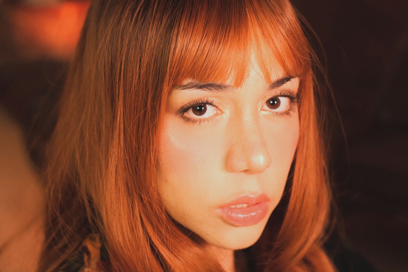 A young woman with vibrant red hair looking forward.