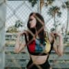 woman in black and red sports bra and black shorts leaning on chain link fence