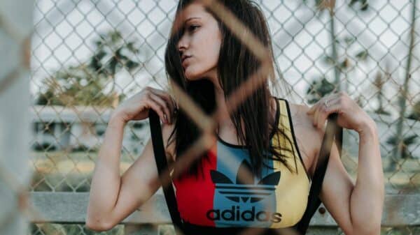 woman in black and red sports bra and black shorts leaning on chain link fence