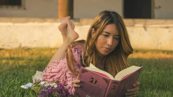 Woman enjoys a book while lounging in the grass.