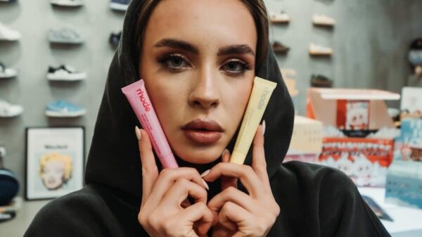 Woman in hoodie holds pink and yellow tubes