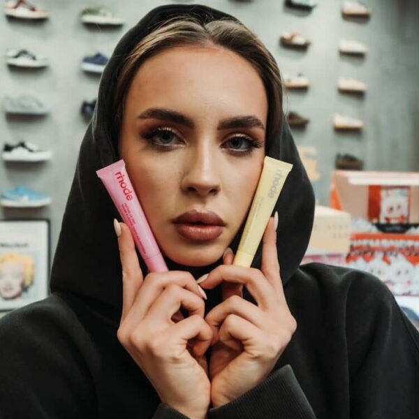 Woman in hoodie holds pink and yellow tubes