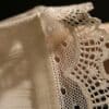 A close up of a person's hand holding a piece of lace