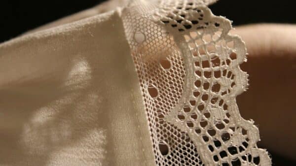 A close up of a person's hand holding a piece of lace