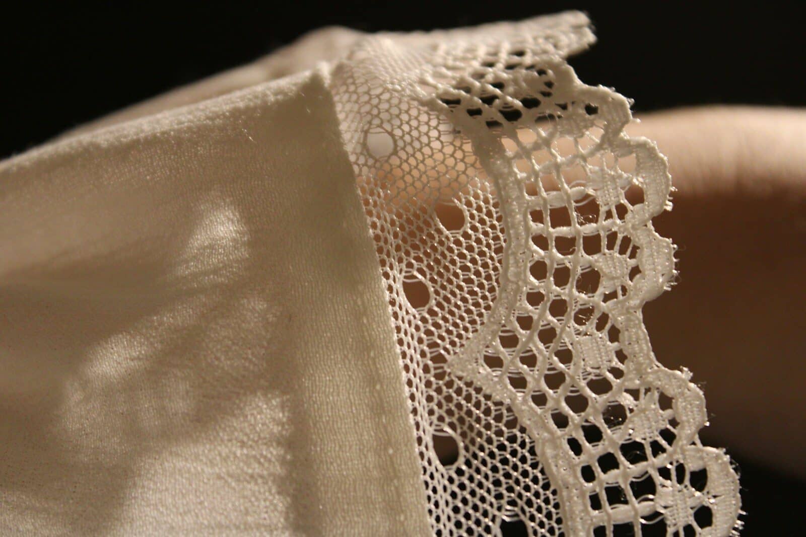 A close up of a person's hand holding a piece of lace