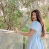 Young woman in blue dress looks over shoulder
