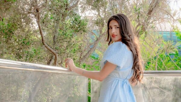 Young woman in blue dress looks over shoulder