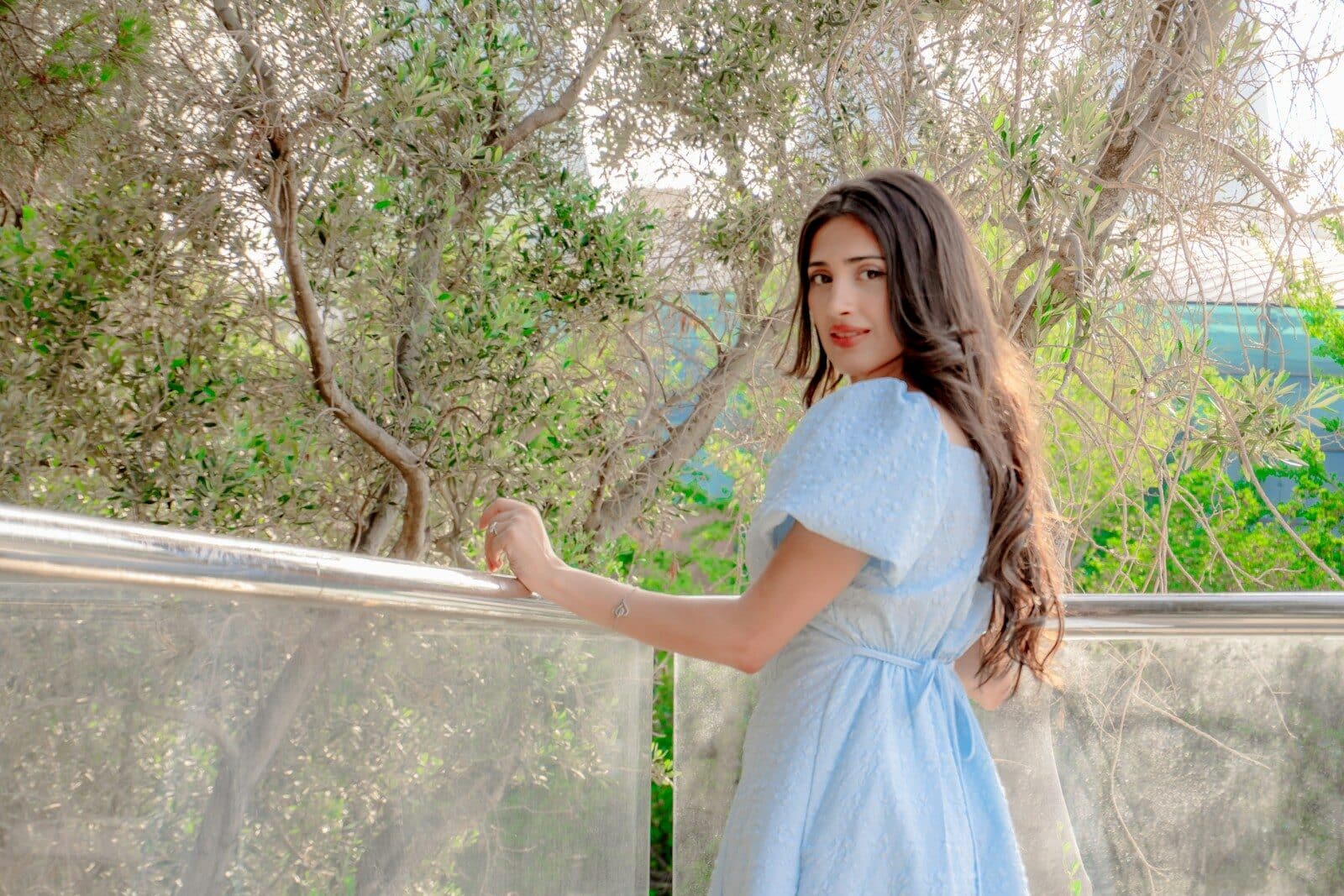 Young woman in blue dress looks over shoulder