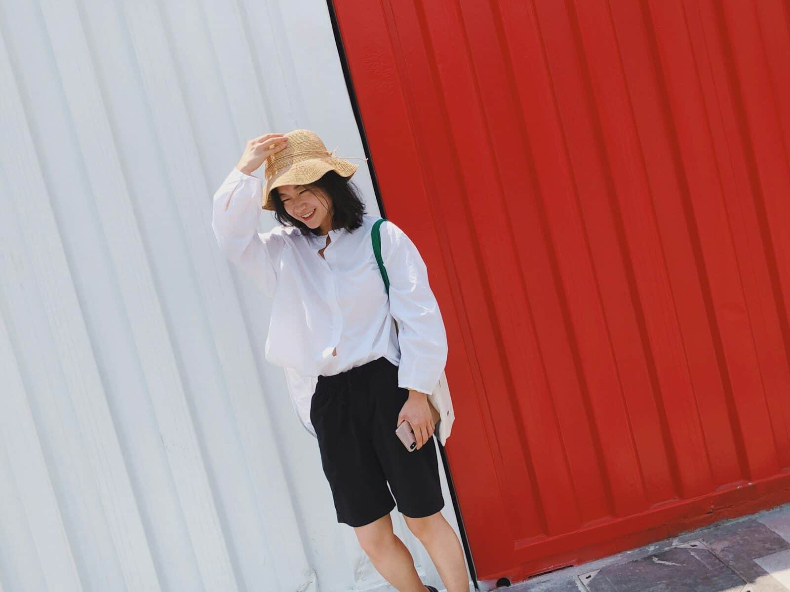 smiling woman standing beside red and white wall