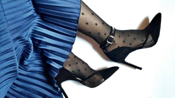 person wearing blue satin skirt and black suede pointed-toe stiletto sandals