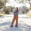 woman in white long sleeve shirt and orange and yellow skirt standing on gray concrete road