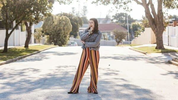 woman in white long sleeve shirt and orange and yellow skirt standing on gray concrete road