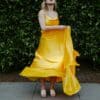 woman in yellow sleeveless dress standing on gray concrete floor