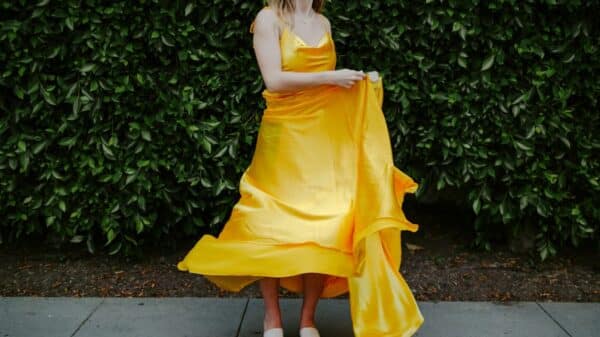 woman in yellow sleeveless dress standing on gray concrete floor