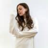 A young woman in a white straitjacket looking down