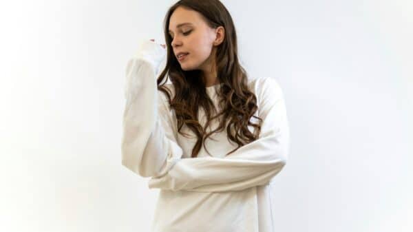 A young woman in a white straitjacket looking down