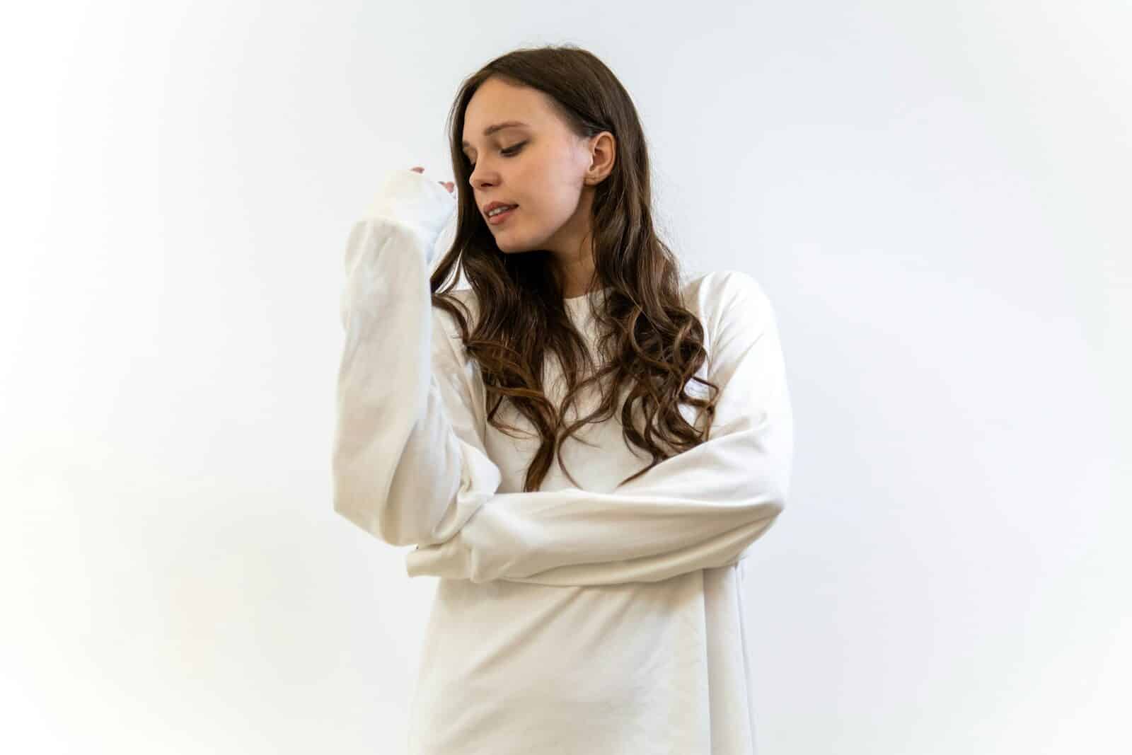 A young woman in a white straitjacket looking down