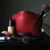 red leather bag beside black makeup brush