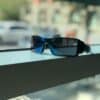 black framed blue lens sunglasses near window